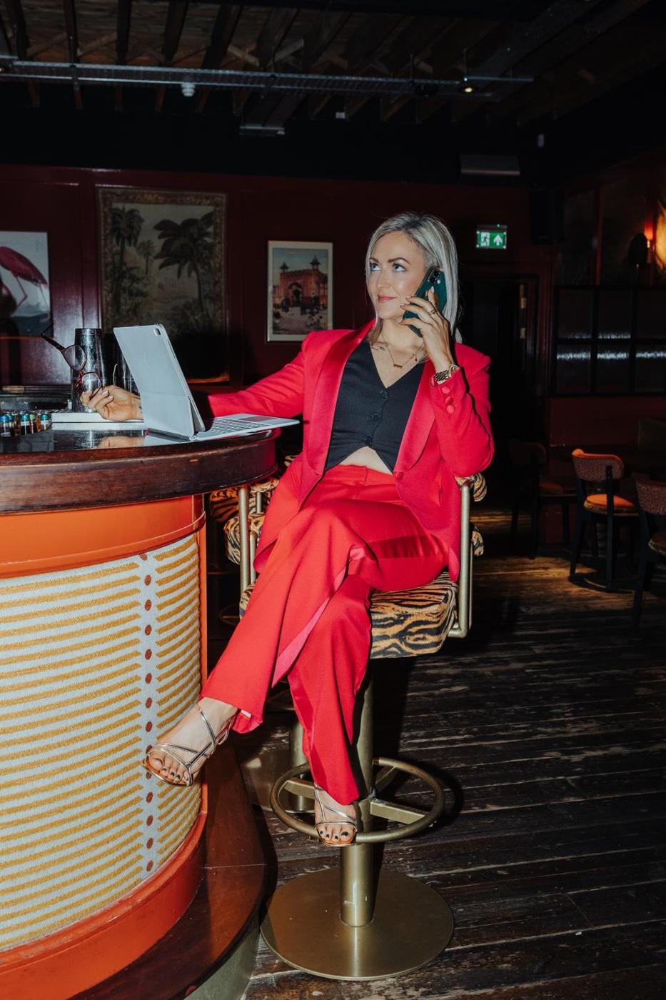 Maria Morgan in a red suit on a phone call