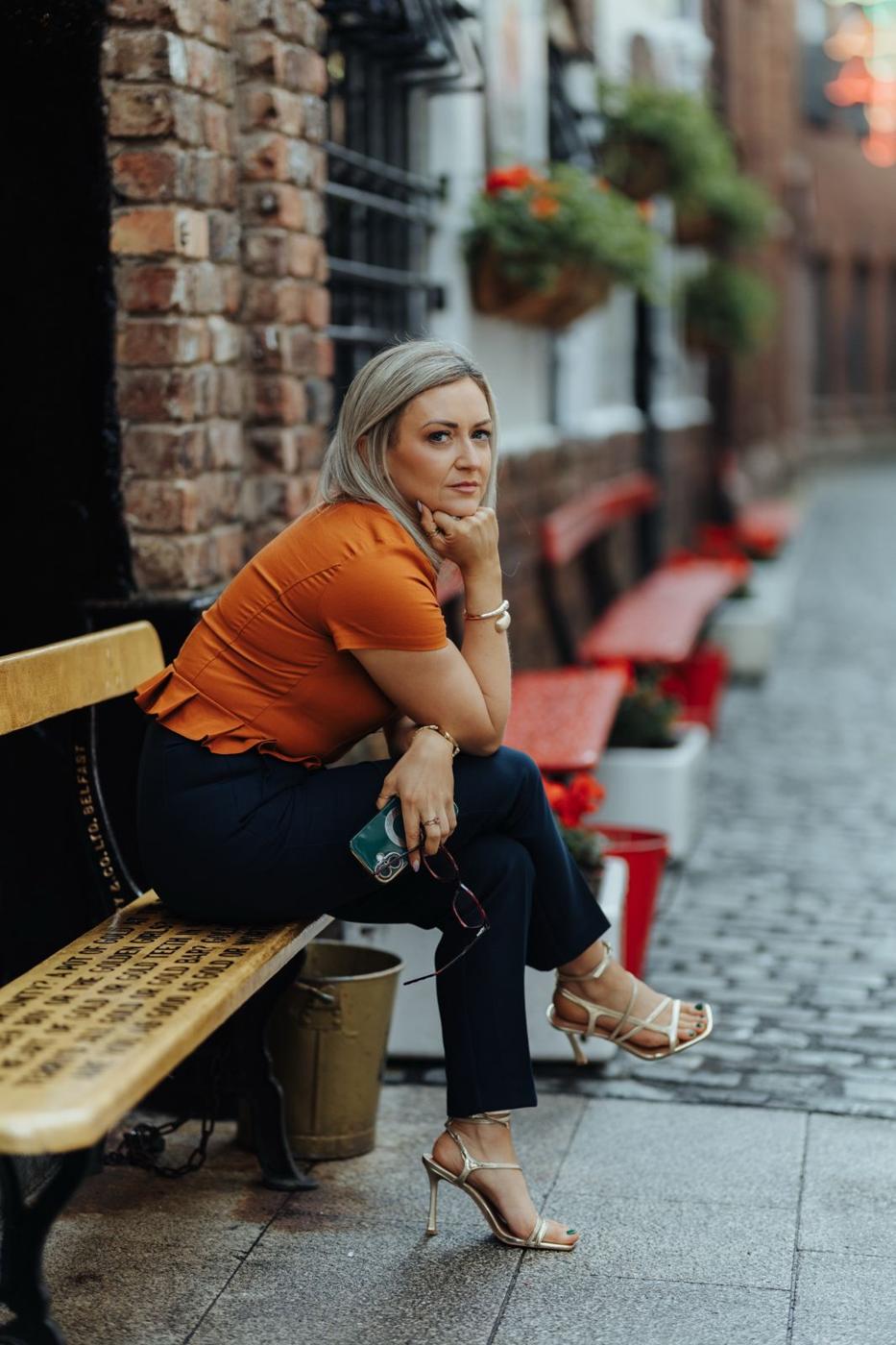 Maria Morgan sitting on a bench in a Belfast entry