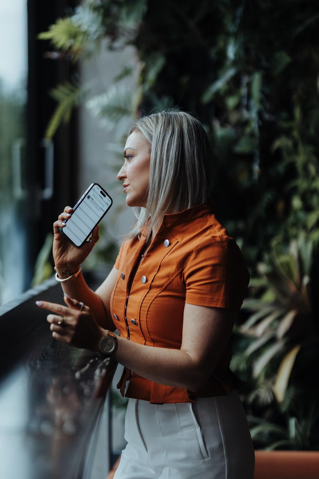 Maria Morgan on the phone beside a window filled with plants